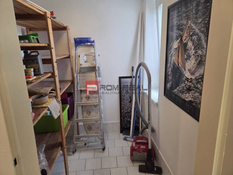 Storage space in a 2-room apartment with shelves, a vacuum cleaner, and a ladder.