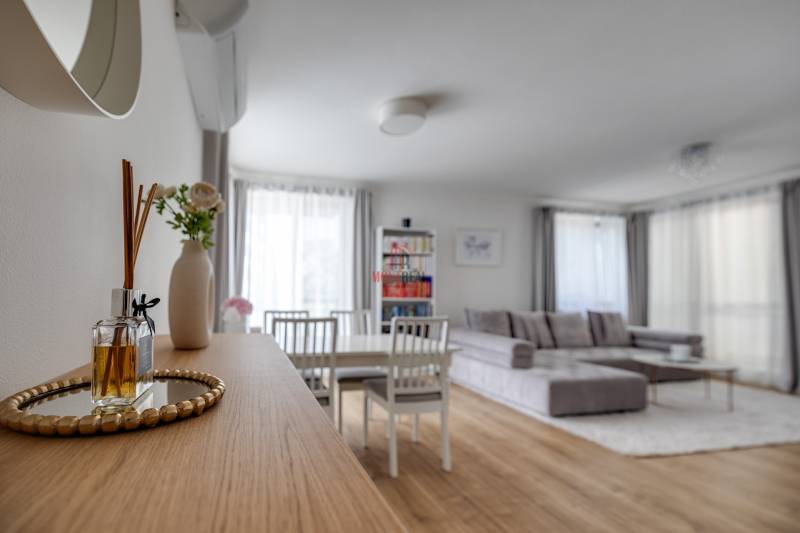 A bright interior of a 3-room apartment with a sofa, dining area, and decorations on a wooden table.