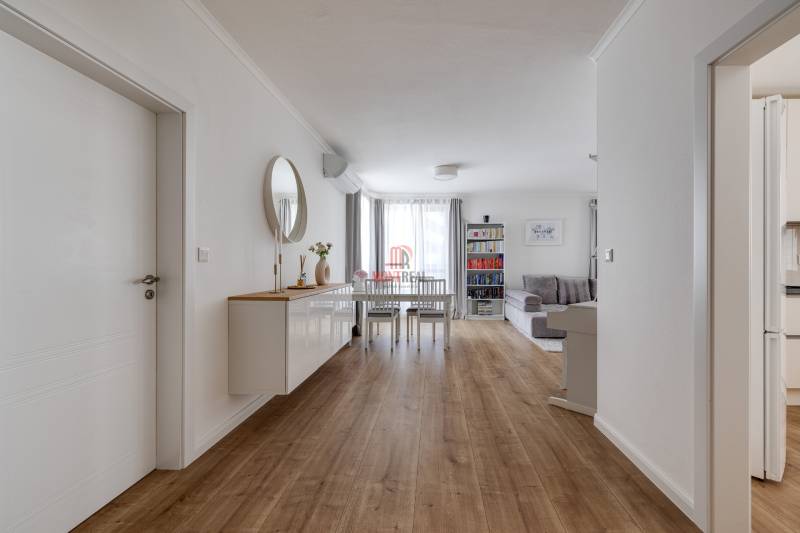 Interior of a 3-room apartment with wooden flooring, a dining table, and a living room.