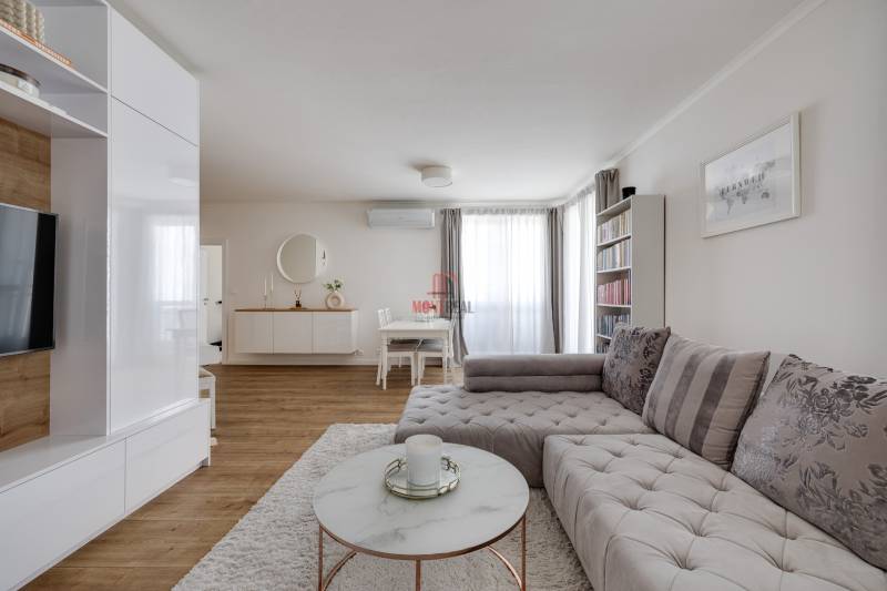 Living room in a three-room apartment with a stylish sofa and minimalist furniture.