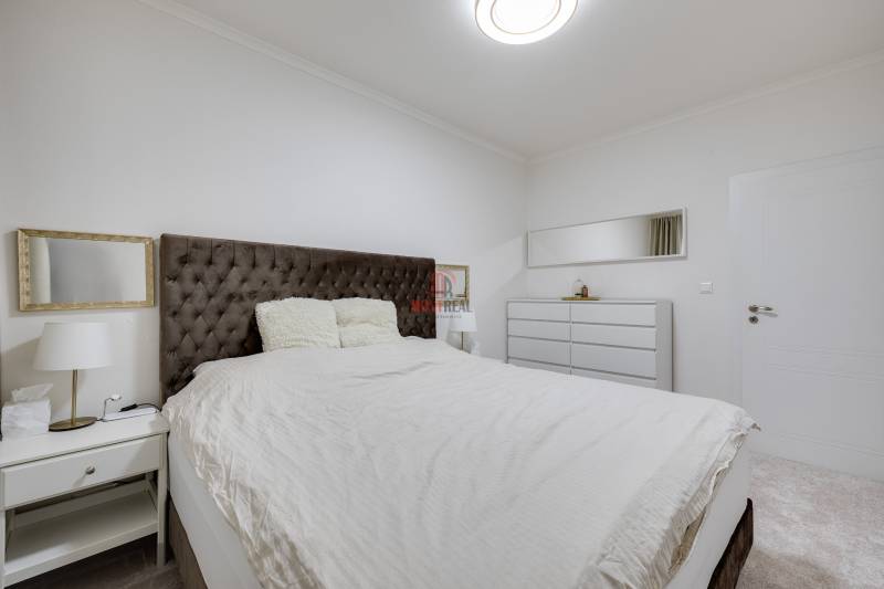 Bedroom with a large bed, nightstand, and dresser in a 3-room apartment.