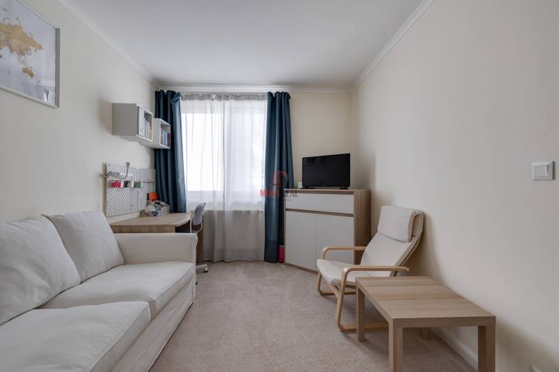 Living room in a 3-room apartment with a comfortable sofa, armchair, and desk.