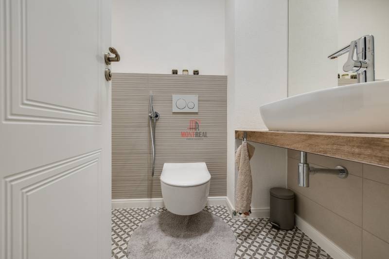 A bathroom with a wall-hung toilet and sink in a 3-room apartment with geometric tiles.