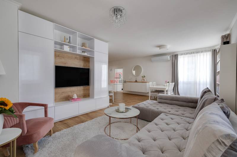 Living room in a 3-room apartment with a comfortable sofa, TV wall, and dining table.