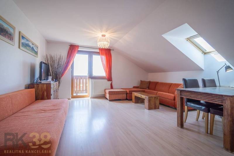 Recreational apartment with an orange sofa and a dining table under a skylight.