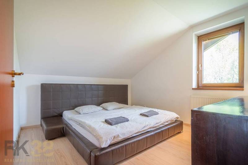 Bedroom in a Holiday Apartment with a double bed, window, wooden furniture, and sloping ceilings.