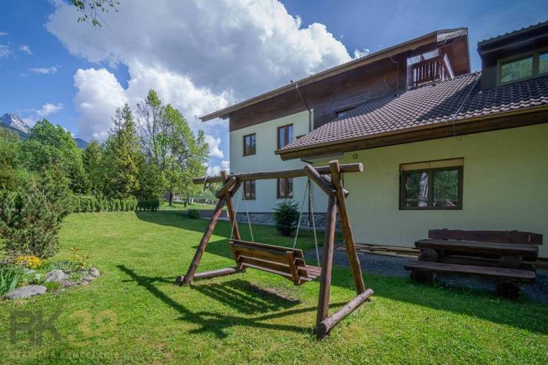 A garden with a wooden swing and a bench at the Recreational Apartment in the High Tatras.