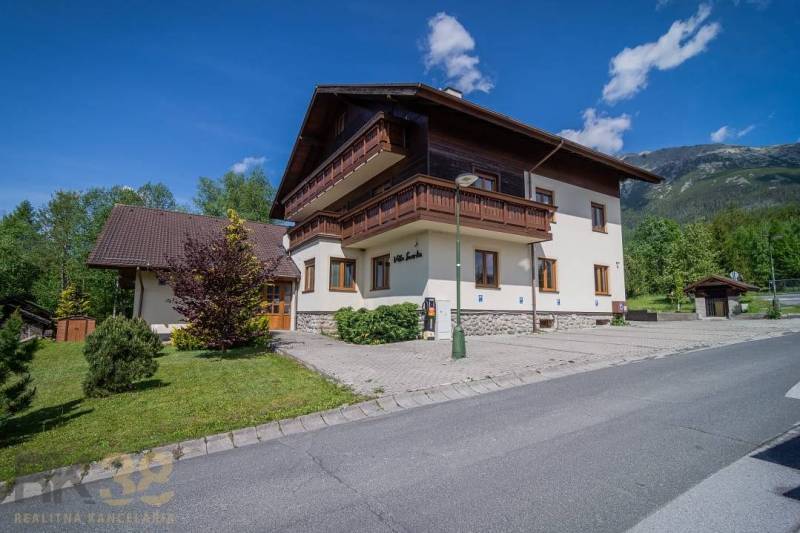 A recreational apartment in the High Tatras, surrounded by greenery, blue sky, mountains in the background.