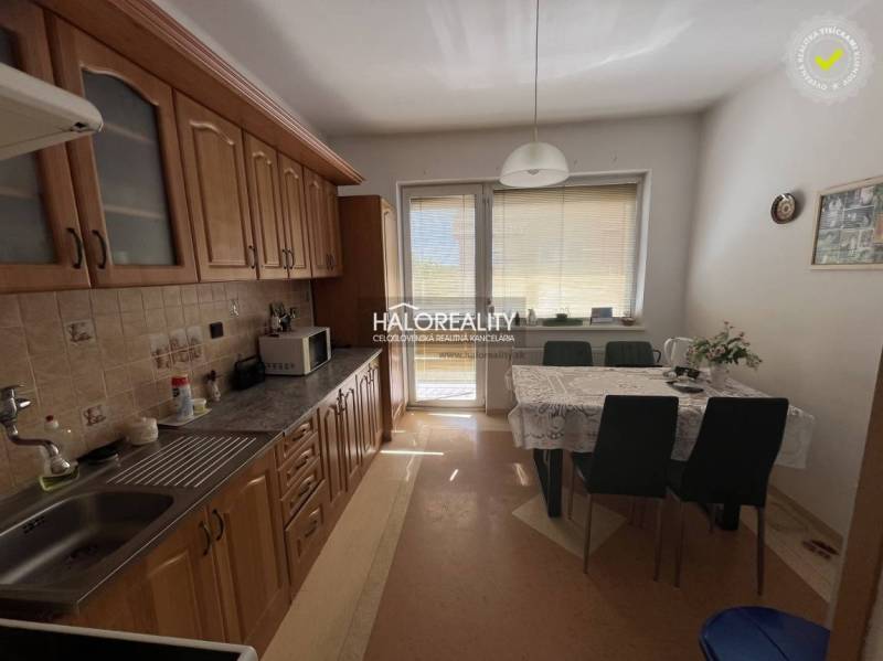A kitchen in a 3-room apartment with a dining table, cabinets, and balcony doors.