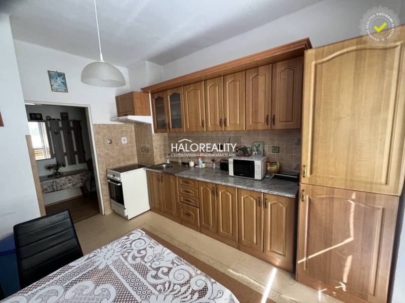 A kitchen in a 3-room apartment with wooden cabinets and equipment, a table with a tablecloth.