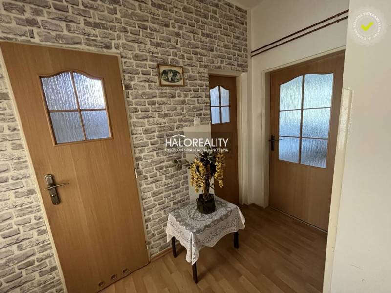 Hallway in a 3-room apartment with wooden doors and decorative wallpaper with a brick pattern.