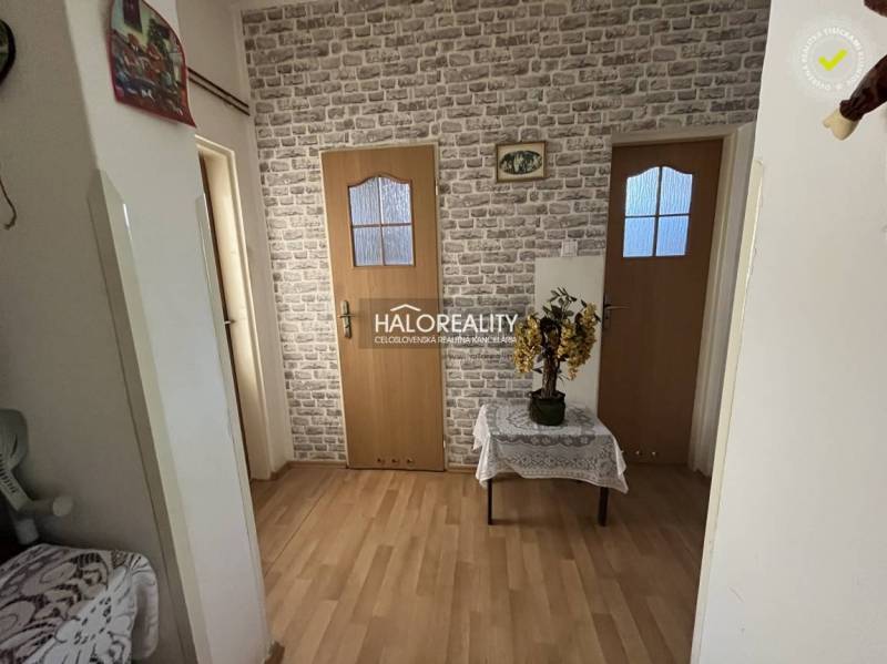 A hallway in a 3-room apartment with a brick pattern on the wall and wooden doors.