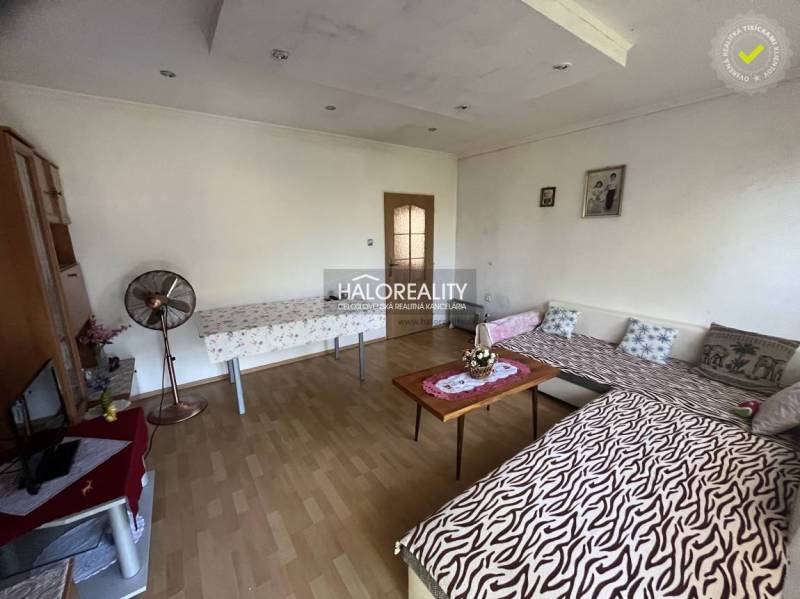 Living room in a three-room apartment with wooden flooring and simple furniture.
