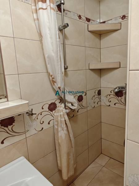 A shower corner with a floral pattern in the tiles in a 2-room apartment.