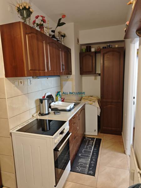 A kitchen in a 2-room apartment with a stove, sink, and wooden cabinets.