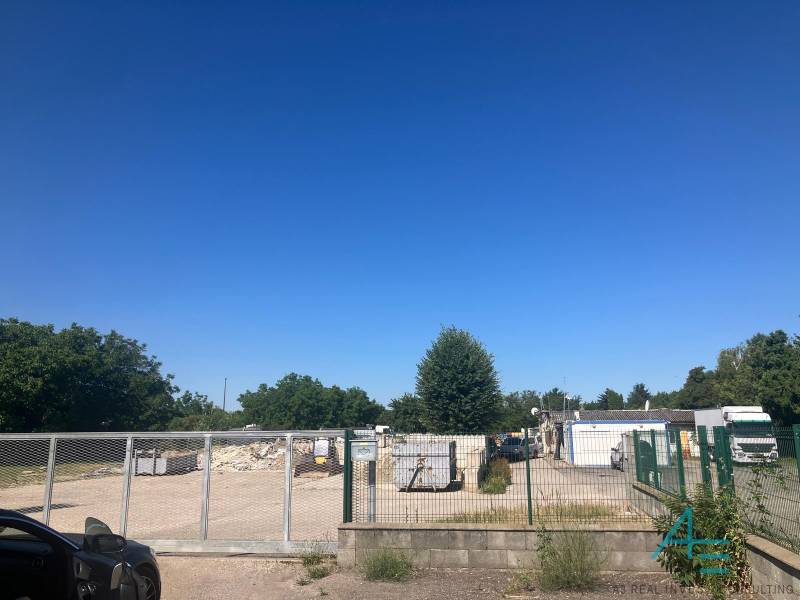 Commercial land on Popradská Street in Bratislava - Podunajské Biskupice with a gate and containers.