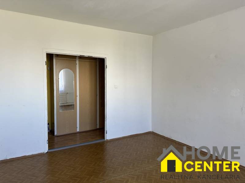 Empty room with white walls and a door with a mirror in a studio apartment.