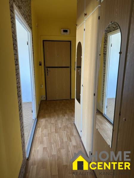 A hallway with a built-in wardrobe in a studio apartment, laminate flooring, yellow walls.