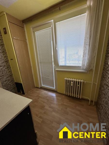 A kitchen in a studio apartment with laminate flooring, a radiator, and a built-in wardrobe.