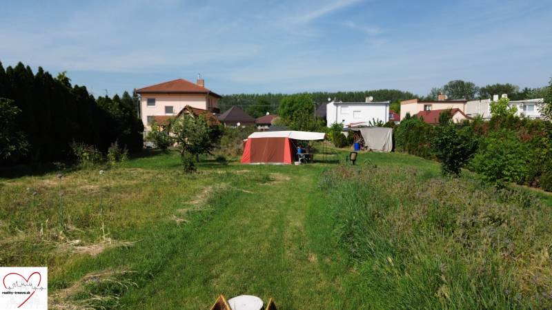 A garden with a lawn in Dolný Bar, with a view of houses and a tent. Plots - housing.