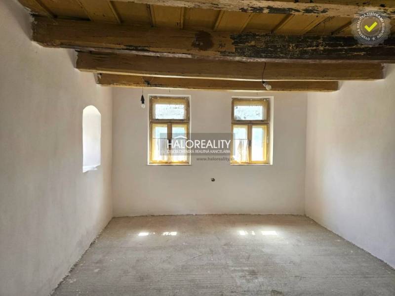 A room with a wooden ceiling and two windows in a family house.