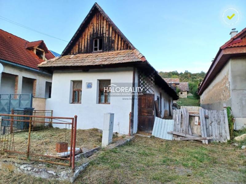 A family house in Ladzany with a sloped roof and a garden, surrounded by other buildings.