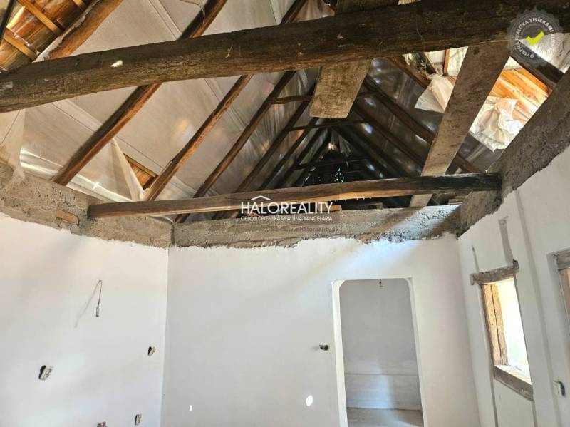 Interior of a family house with exposed wooden roof beams and white plastered walls.