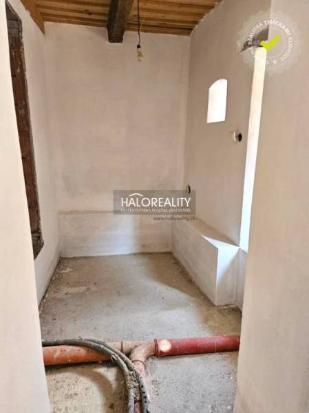An untidy room in a family house with visible construction elements and a beamed ceiling.