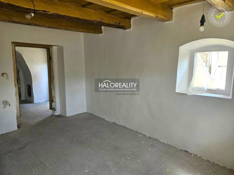 Interior of a family house with light painting, wooden ceiling, and a small window.