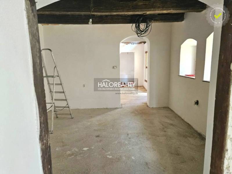An unfinished interior in a family house with exposed wooden beams and a ladder.