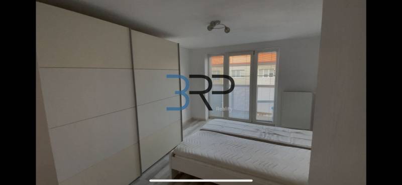 A room in a 2-bedroom apartment with a bed, built-in wardrobe, and French window.