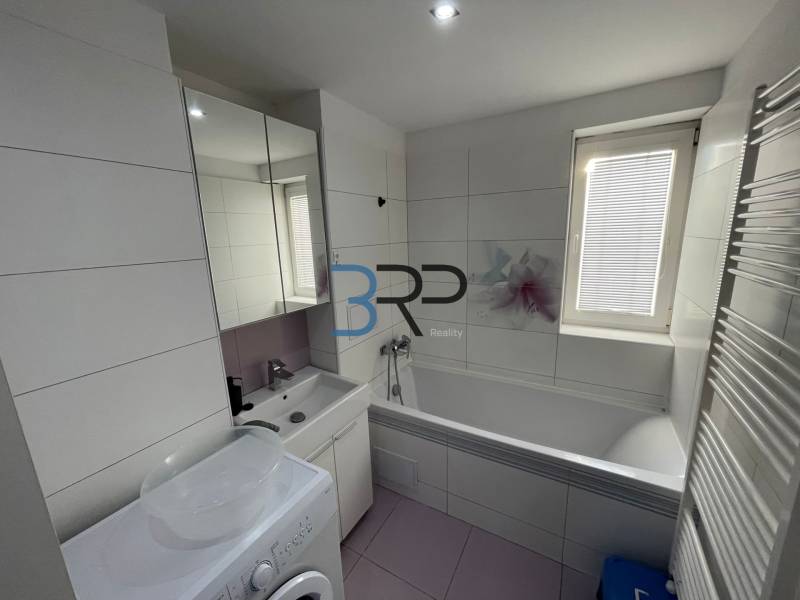 Bathroom in a 2-room apartment with a bathtub, sink, and washing machine.