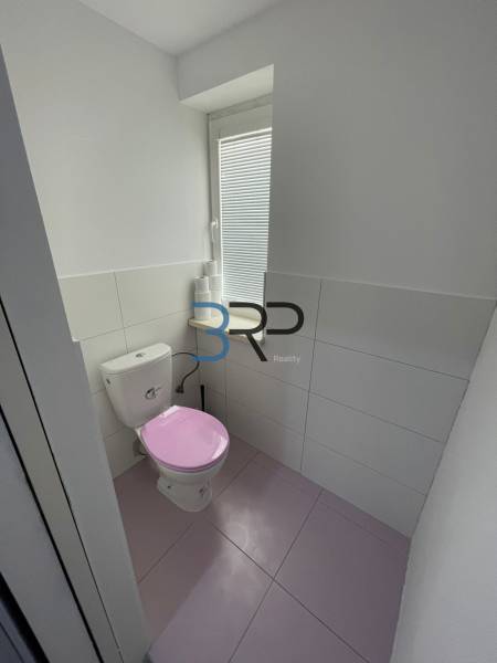 A bathroom in a 2-room apartment with a pink toilet and white tiles.