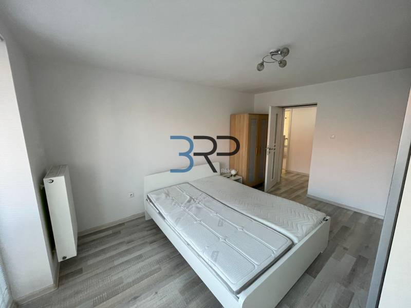 Bedroom in a 2-room apartment with a bed, wardrobe, and white walls.