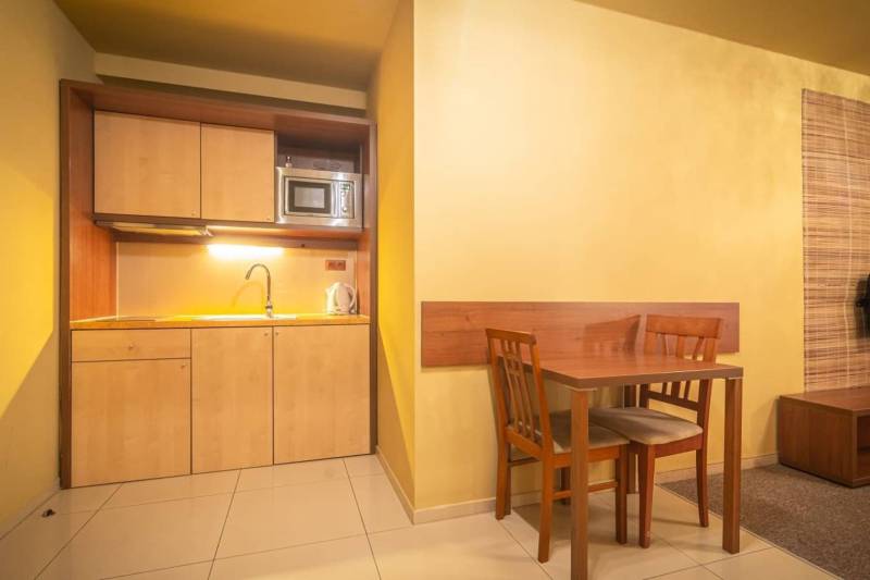 Kitchen corner with a sink, microwave, and dining table in a holiday apartment.