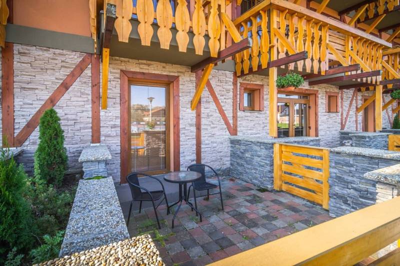 Stone terrace of the Holiday Apartment in Veľká Lomnica with wooden railing and a table.
