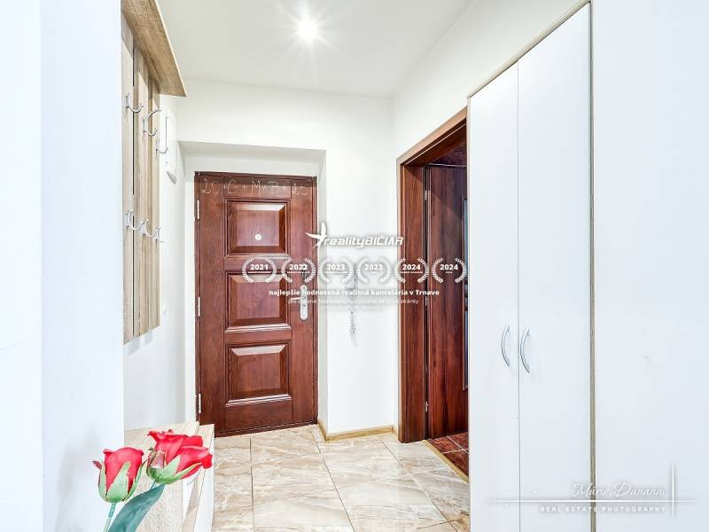 Entrance hall of a 2-room apartment with wooden and white cabinets and tiles.