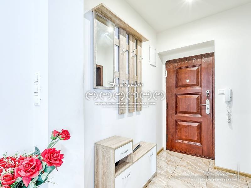 Entrance hall in a 2-room apartment with wooden doors and a mirror, decorated with red flowers.