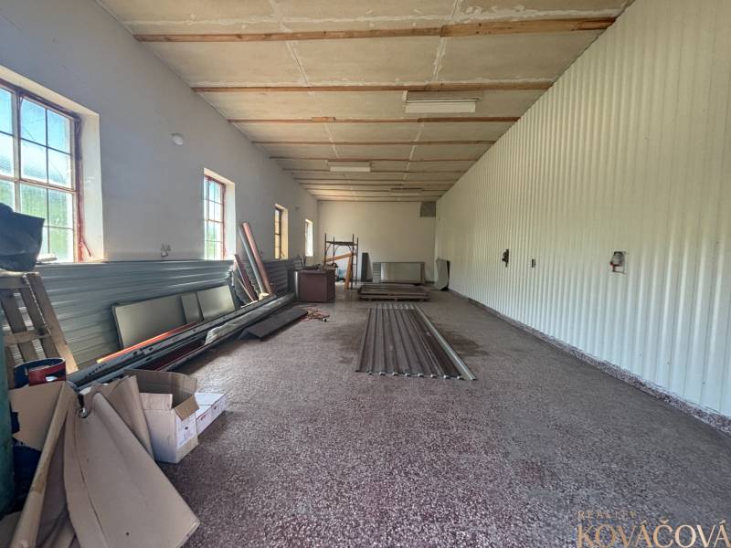 The interior of a hall with storage materials and windows on one side.