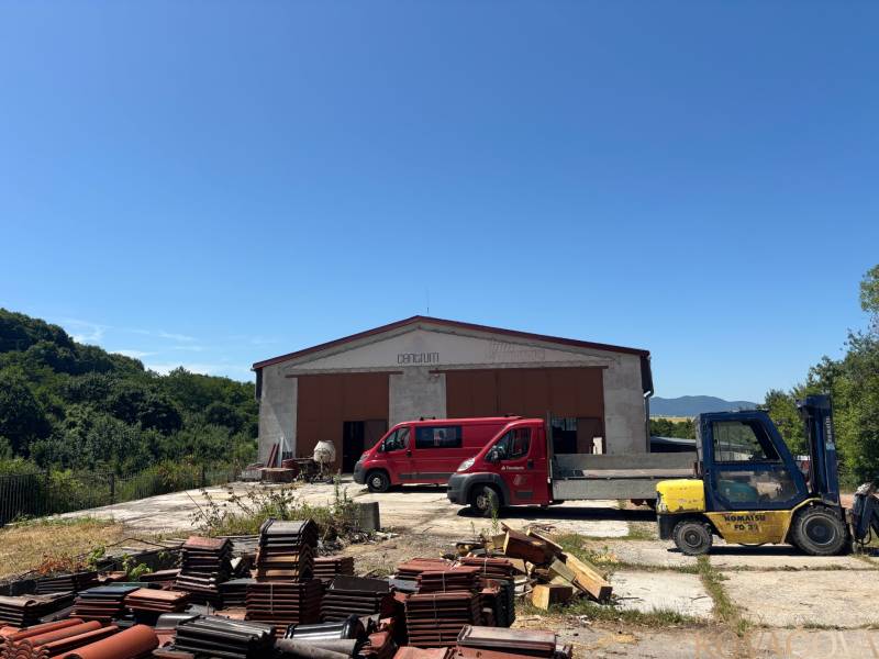 Warehouses and halls in Mníchova Lehota with stacks of bricks, a red van, and a forklift.