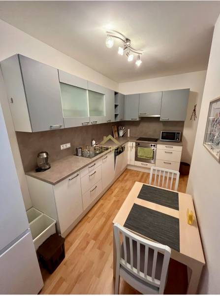 A kitchen in a 2-room apartment with wooden flooring and modern appliances.