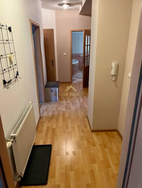 A hallway in a 2-room apartment with a wooden floor, a coat rack, and an entrance to the bathroom.