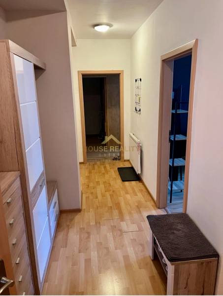 A hallway in a 2-room apartment with light wooden furniture and open doors.