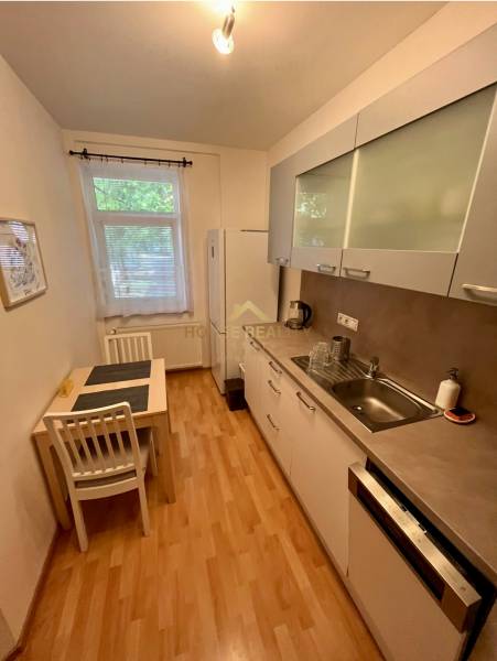 Kitchen in a 2-room apartment with a dining table, white cabinets, and appliances.