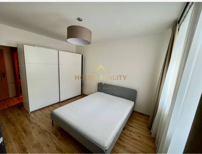 Bedroom in a two-room apartment with a double bed, built-in wardrobe, and wooden floor.