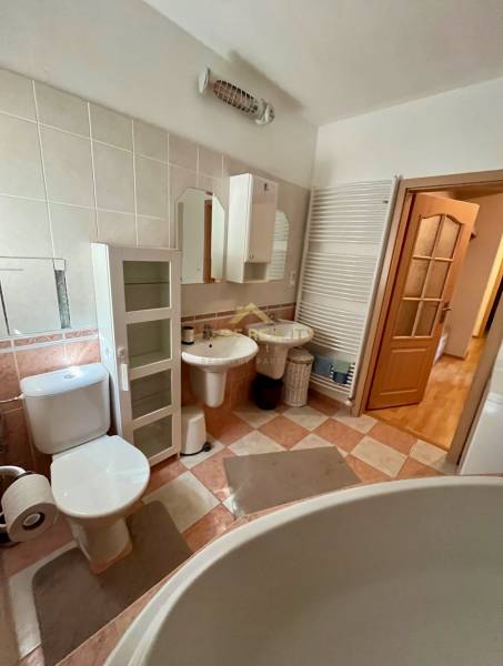 Bathroom of a 2-room apartment with sanitary ware, cabinets, and a large bathtub.
