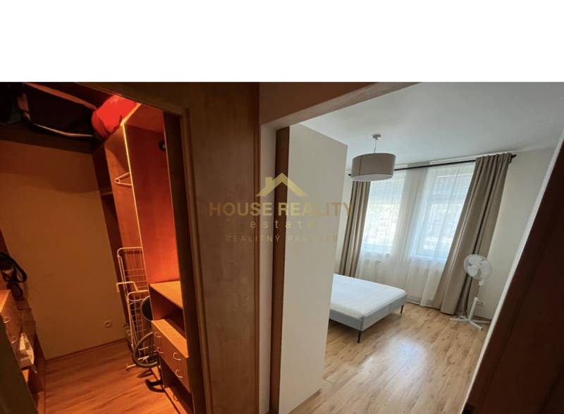 Bedroom in a 2-room apartment with a built-in wardrobe and bed, light curtains.