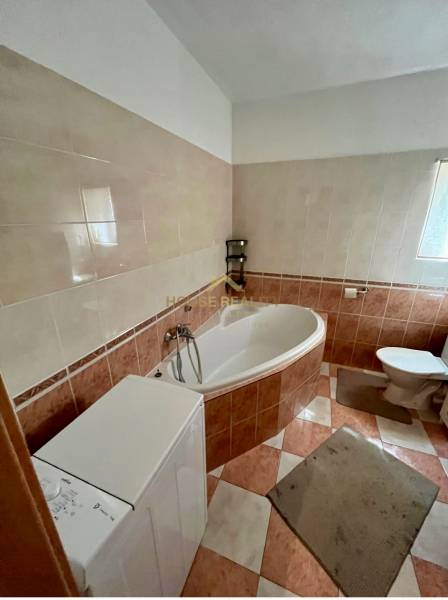 Bathroom in a 2-room apartment with a bathtub, washing machine, and toilet.