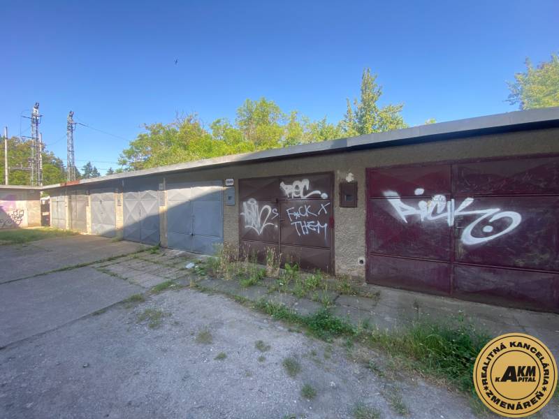 Garages in Zvolen with graffiti on the doors, surrounded by greenery and a concrete area.
