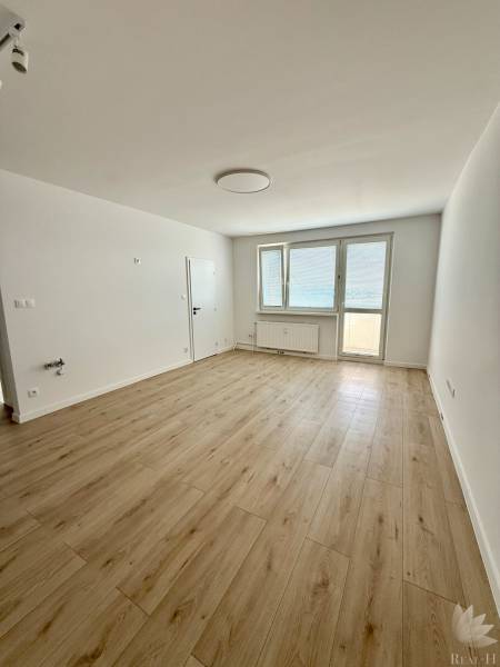 An empty room with a wooden floor and a large window in a two-room apartment.